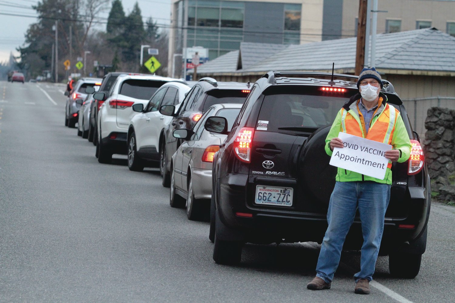 Volunteer David Tinker helps drivers get in the queue for Jefferson Healthcare’s drive-thru immunization clinic in Port Townsend last Thursday. At one point, the line of vehicles stretched from the hospital to Sims Way West.